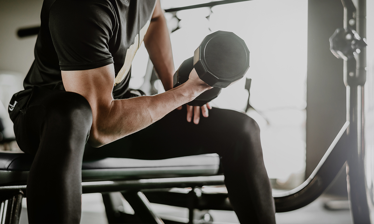 A man lifting an Everfit dumbell in a gym.