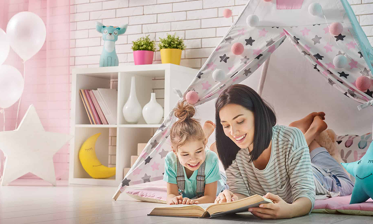 A woman and child reading a book inside a child's tent.